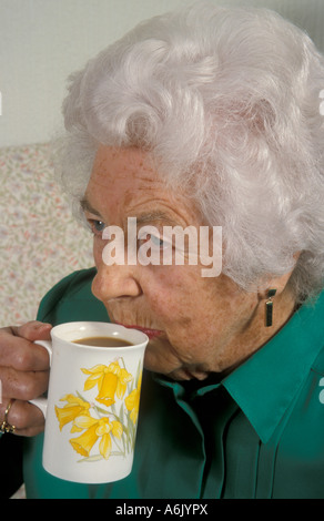 elderly woman drinking cup of tea/coffee from mug Stock Photo