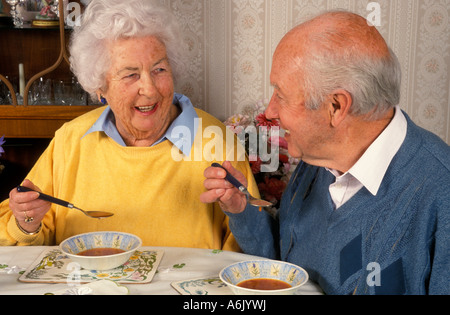 happy elderly couple eating soup at dining table Stock Photo