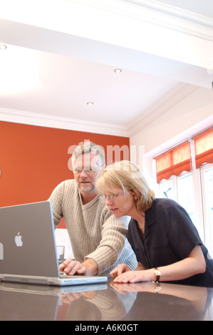 British business man and woman remote working from home London UK with apple mac Laptop Stock Photo