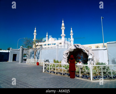 Dubai UAE Christian Woman Praying at Shrine of St Mary Outside of St Marys Catholic Church with Minarets in Background Stock Photo