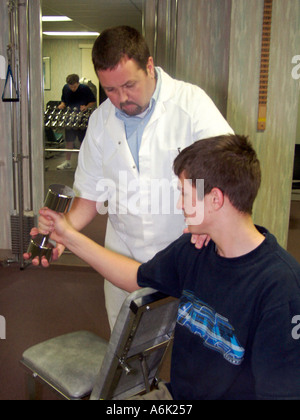 Physical therapist working with young athlete in sports gym Stock Photo