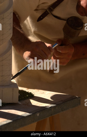 French Stonemason in period costume carving stone spiral, close up    of using mallet and chisel in monflanquin aquitaine south west france eu Stock Photo