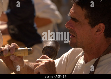 French Stonemason, man in french period costume carving stone in closeup,using mallet and chisel at medieval festival, Monflanquin Aquitaine france eu Stock Photo