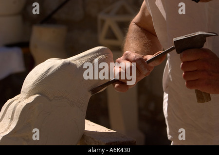 French Stonemason, stone sculptor, close up of man in french period costume carving stone head using mallet and chisel, Aquitaine France europe eu Stock Photo