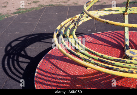 Children's roundabout casting a shadow on the ground in childrens playground, Heston London, UK Stock Photo