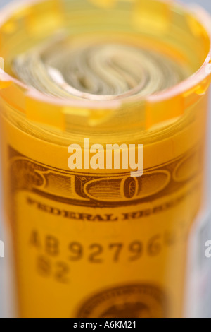 Pill bottle with 100 dollar bill inside close up Stock Photo