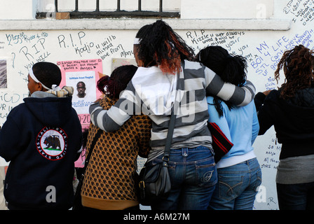 Friends and family of Kodjo Yenga perusing the wriiten tributes near Hammersmith Grove, west London, UK where he was knifed to death. Stock Photo