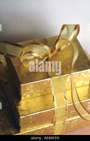 Stack of Three 3 Gold Gift Boxes Tied Together with Gold Ribbon Copy Space Stock Photo