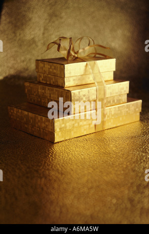Stack of Three 3 Gold Gift Boxes Tied Together with Gold Ribbon Copy Space Stock Photo