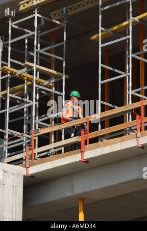 Construction worker at work surrounded by scaffolding on a new build office complex Stock Photo