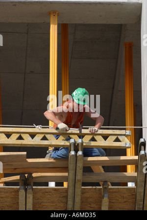 Construction worker at work hammering nails on a new build office complex Stock Photo