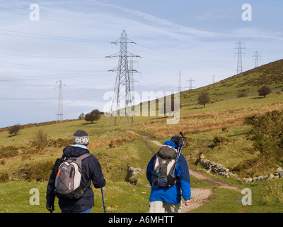 Ugly electricity pylons across North Wales Path with walkers in countryside in Snowdonia National Park Gwynedd Wales UK Britain Stock Photo