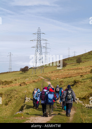 Ugly electricity pylons across North Wales Path with walkers in countryside in Snowdonia National Park Gwynedd North Wales UK Stock Photo