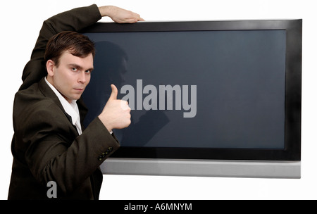 Businessman recommending a plasma TV showing thumb up Stock Photo