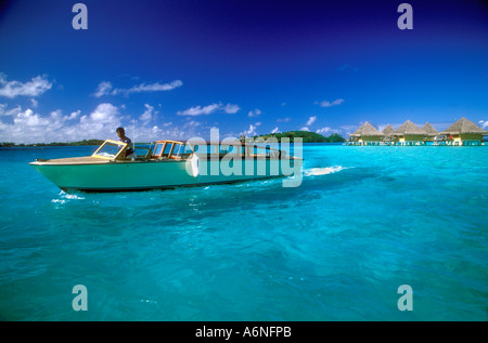 Shades of turquoise waters , thatched bungalows and water taxi , Bora Bora Stock Photo
