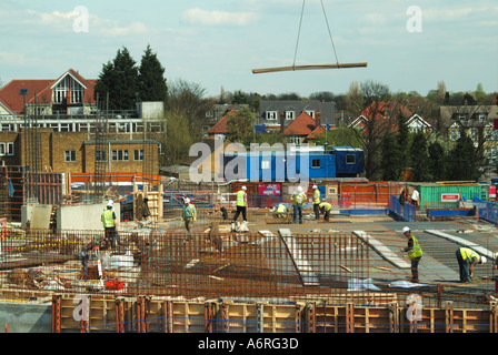 Crane lowering steel bars on  large reinforced concrete construction site at first floor level London England UK Stock Photo