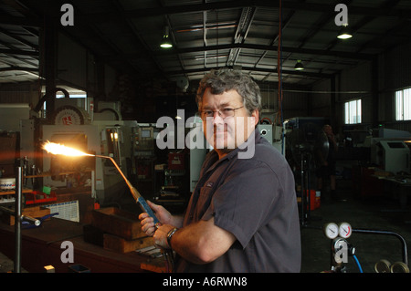 Worker prepares to heat steel in metals workshop with blowtorch Stock Photo