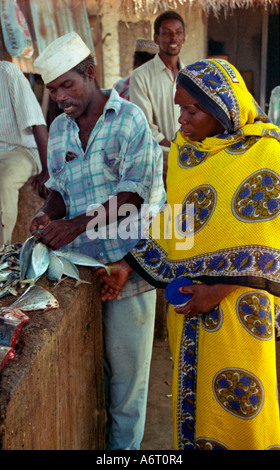 Zanzibar Tanzania East Africa A young Zanzibari women wearing the traditional khanga buying freshly caught fish. Mkotoni village Stock Photo