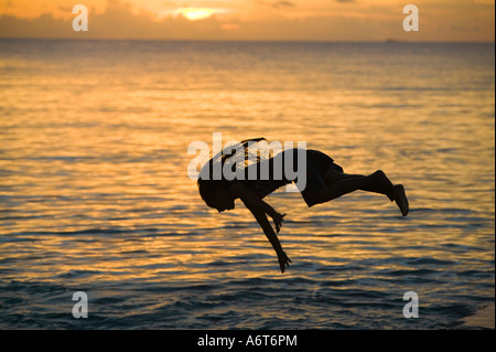 Children leaping into the sea from a jetty on Funafuti island at sunset, Tuvalu, Pacific Stock Photo
