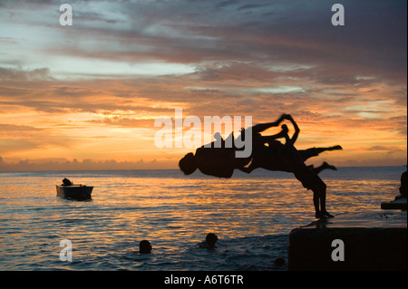 Children leaping into the sea from a jetty on Funafuti island at sunset, Tuvalu, Pacific Stock Photo