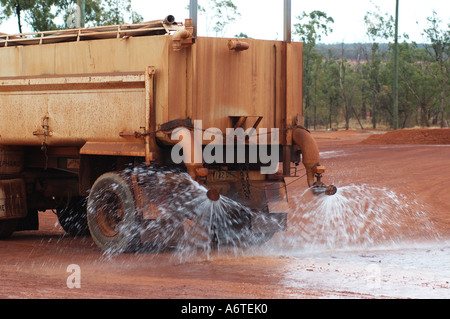 Water tanker suppresses red dust and earth at mine site Stock Photo - Alamy