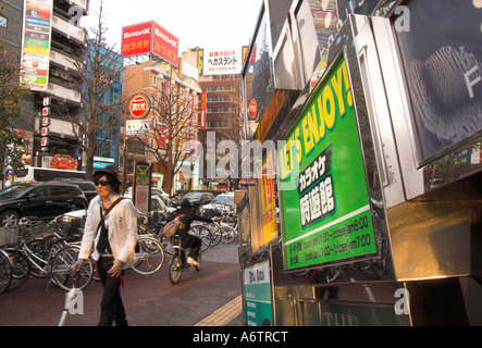 Japan Nothern Honshu Miyagi Ken Sendai shopping area modern buildings advertising posters bicycles and stylish young man walking Stock Photo