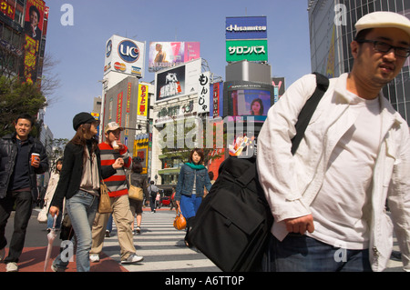 Japan Central Honshu Tokyo Shibuya Main junction group of youngsters crossing the road with advertising posters and huge video s Stock Photo