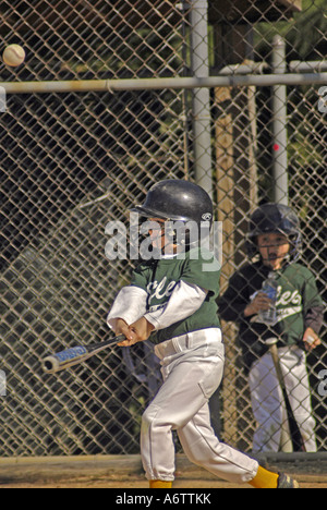 Boys age 6 7 playing little league baseball batting batter hits ball Stock Photo