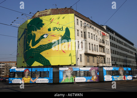 Colorful comic tram in front of huge advertisement banner that promotes apples ipod on abuilding facade in Berlin, Germany, Eur Stock Photo