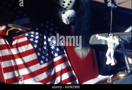 elvis doll hanging from rear view mirror with american flag in background and furry dice Stock Photo