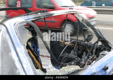 Burnt out car on a road Stock Photo