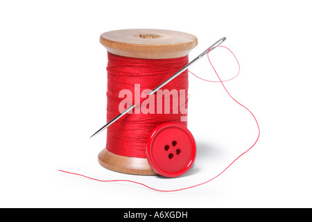 Spool of thread, needle and button cut out on white background Stock Photo