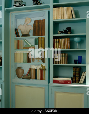 Close-up of books on blue shelves beside painted door with  trompe-l'oiel shelves