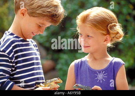 portrait of a boy and a girl playing with a plastic frog toy
