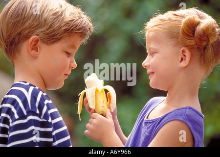 portrait of a boy and a girl eating a banana