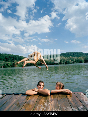 A young man diving into a lake with friends