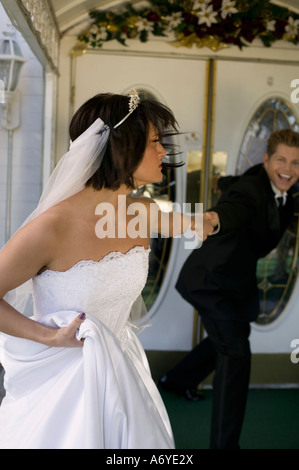 Groom dragging bride into a wedding chapel Stock Photo