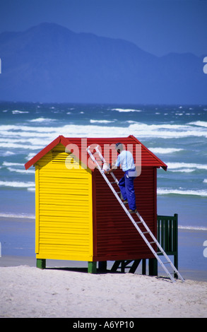 Man painting yellow beach hut at Calshot Beach 