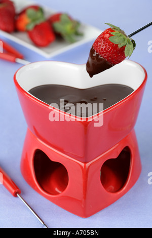 Heart shaped chocolate fondue dipping a strawberry  Stock Photo