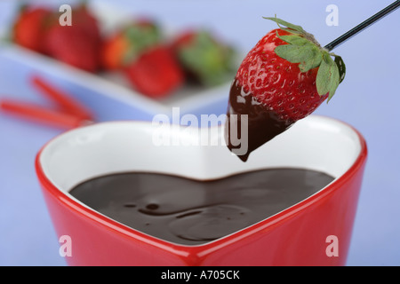 Heart shaped chocolate fondue dipping a strawberry  Stock Photo