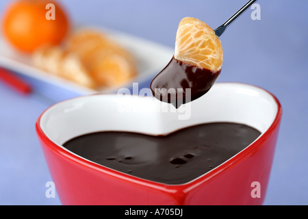 Heart shaped chocolate fondue dipping a tangerine segment  Stock Photo