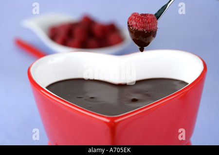 Heart shaped chocolate fondue dipping a raspberry  Stock Photo