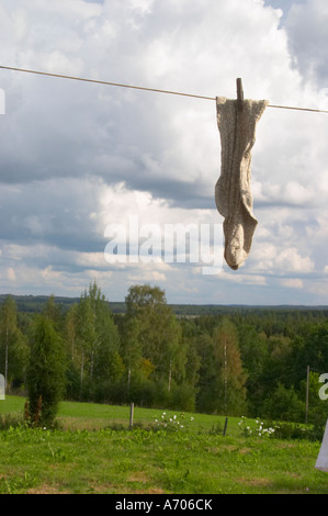 A pair of socks hanging to dry on a clothes line with clothes pins a summer day with clouds in the sky. Smaland region. Sweden, Stock Photo
