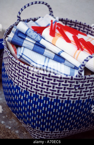 Laundry basket woven in coloured plastic filled with carefully ironed tea towels and linens Stock Photo