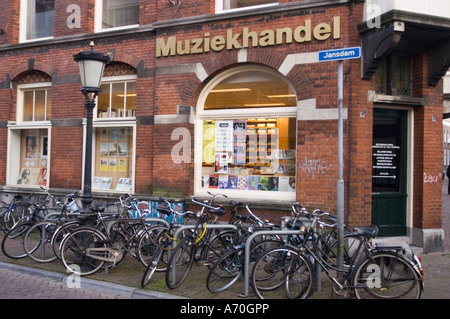 Lot of bikes parking next to music shop on Jansdam street in Utrecht Holland. Traditional Dutch red brick building and street lamp in the city. Stock Photo