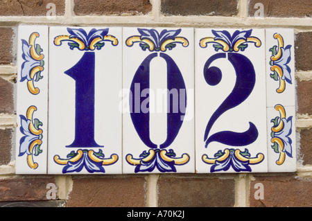102 one hundred two sign on house in Edam, Holland. Decorative blue ceramic tiles with floral patterns mounted on a brick wall. Stock Photo