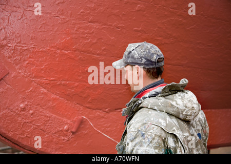 Workmen Boat painting. Ships, nautical, transport, fishing, wooden, painter at MacDuff ship & fishing boat repair yard north-east Scotland UK Stock Photo