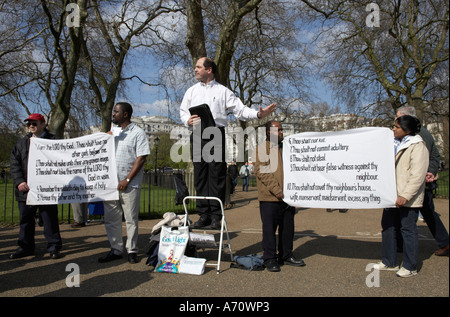 Speaker of a christian denomination is promoting his religion with the help of followers and banners at Speakers Corner in Hyde Stock Photo