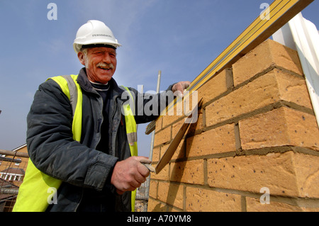 Experienced older bricklayer laying bricks on a housing development Stock Photo