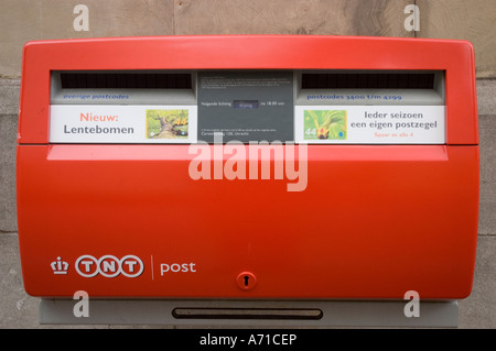TNT Post modern red Dutch letter box on a post office wall in Utrecht, Holland. Features two mail slots and collection information. Stock Photo
